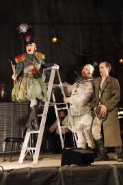 Jamie Van Eyck, mezzo-soprano, as Drummer, announces Emperor Überall's proclamation of war as Harlequin (tenor John Mac Master) and Death (bass Kevin Burdette) look on, 2011