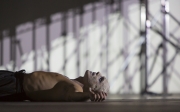 Yury Yanowsky as the Man lay prone and exhausted in Boston Lyric Opera’s new “Opera Annex” production of Philip Glass’s dystopian “In the Penal Colony” based on the Franz Kafka short story in a limited run Nov 11-15 at the historic Cyclorama at the Boston Center for the Arts.