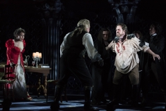 After being accused of harboring an escaped criminal and tortured, Cavradossi (r., Jonathan Burton) vows revenge on Scarpia (c., Daniel Sutin) as Tosca (l., Elena Stikhina) looks on helplessly in the Boston Lyric Opera production of TOSCA, running Oct 13-22 at the Cutler Emerson Majestic Theater. Tickets BLO.org.