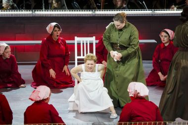 As an Aunt (Jessica Johnson Brock) looks on, Ofwarren (Kathryn Skemp Moran) prepares for childbirth in Boston Lyric Opera’s production of “The Handmaid’s Tale,” running through May 12. BLO.org.