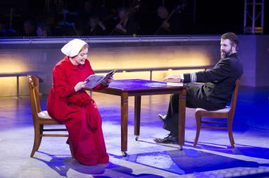 In the Commander’s office (David Cushing), Offred (Jennifer Johnson Cano) reads aloud from a beauty magazine published in the Time Before in Boston Lyric Opera’s production of “The Handmaid’s Tale,” running through May 12. BLO.org.