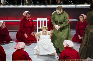 As an Aunt (Jessica Johnson Brock) looks on, Ofwarren (Kathryn Skemp Moran) prepares for childbirth in Boston Lyric Opera’s production of “The Handmaid’s Tale,” running through May 12. BLO.org.